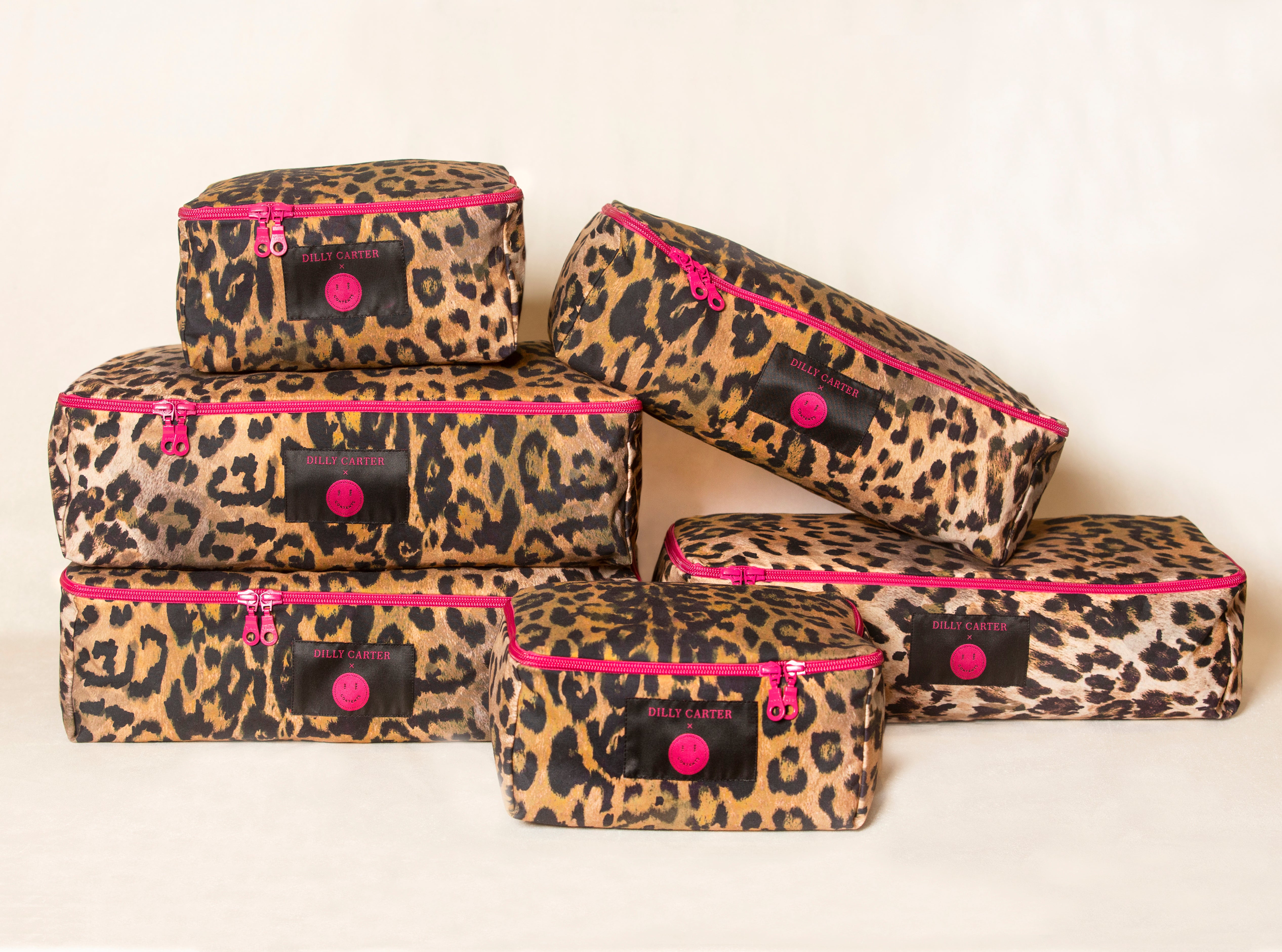 Set of leopard print packing cubes with pink accents on a white background