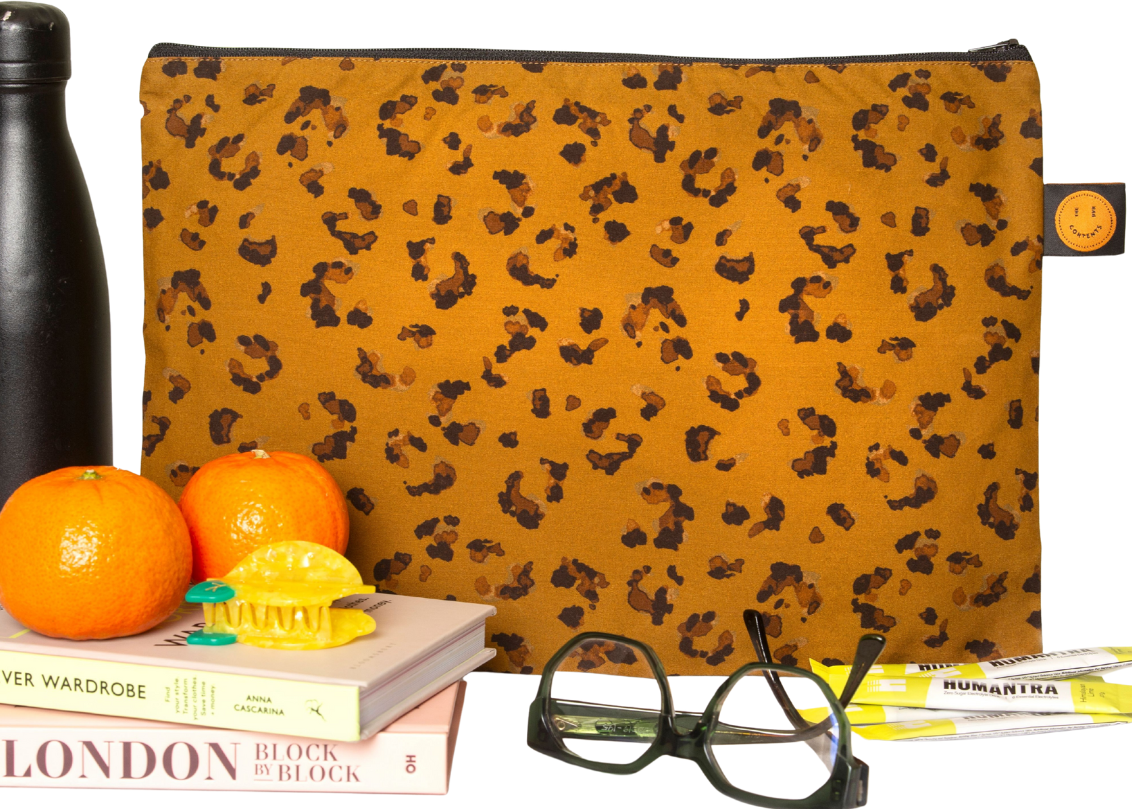 Leopard print pouch with a water bottle, oranges, book, glasses, and notebook on a white background